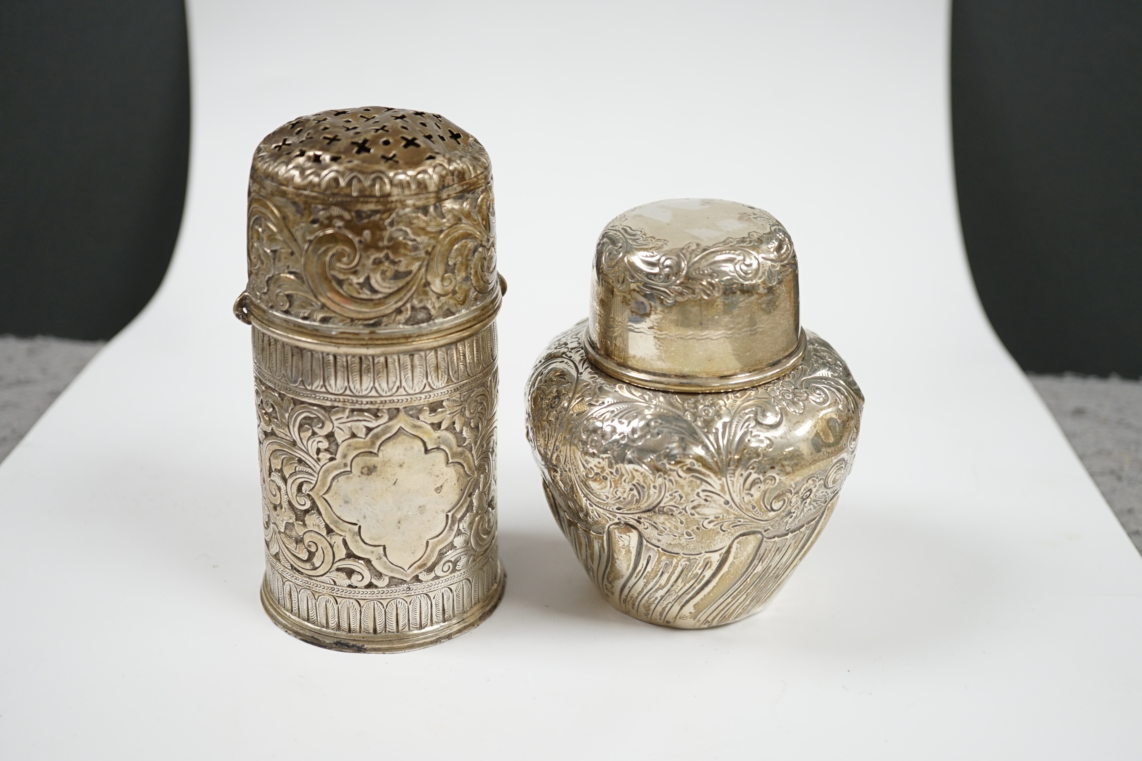 A late Victorian repousse demi-fluted wrythened silver tea caddy and cover, W & C Sissons, London, 1895, 10.3cm, together with a similar repousse silver lighthouse sugar caster, London, 1888, 10oz. Condition - poor